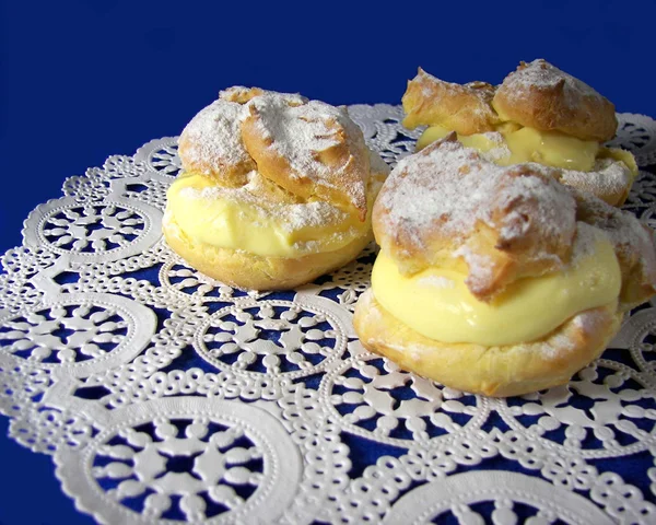Cream puffs on lace doily — Stock Photo, Image