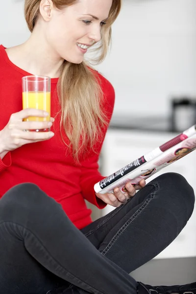 Mladá žena čte časopis doma — Stock fotografie