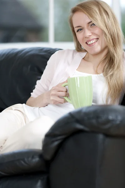 Женщина наслаждается напитком на диване — стоковое фото