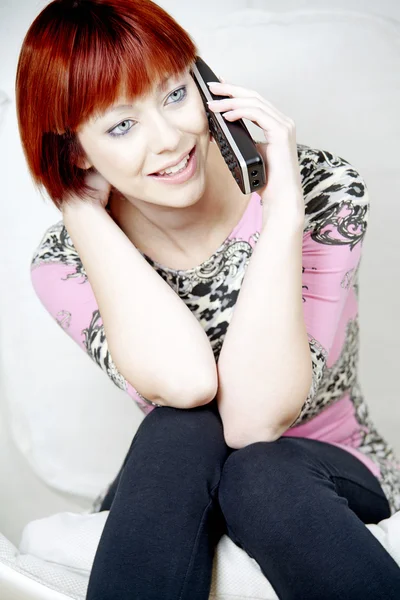 Jovem mulher sentada e conversando ao telefone — Fotografia de Stock