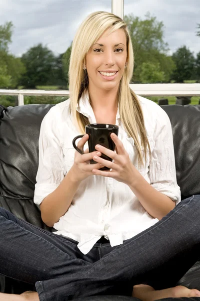 Ung kvinna sitter på soffan — Stockfoto