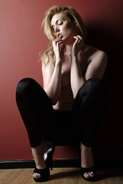 Genç kadın kırmızı bir duvara siyah pantolon — Stok fotoğraf