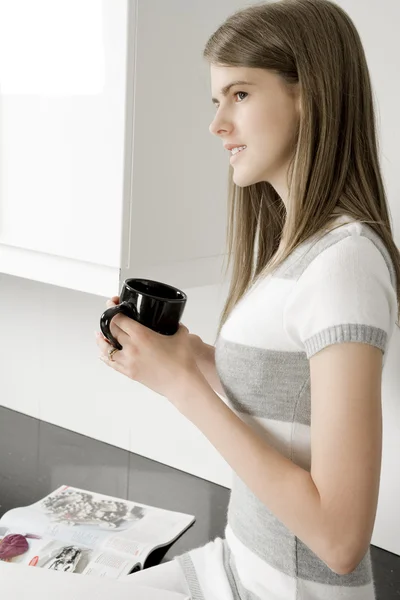 Jovem mulher relaxante em sua cozinha — Fotografia de Stock