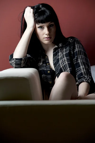 Jeune femme relaxant contre le mur rouge — Photo