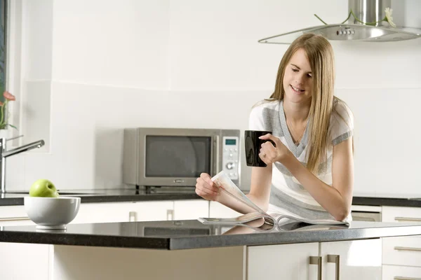 Jovem mulher relaxante em sua cozinha — Fotografia de Stock