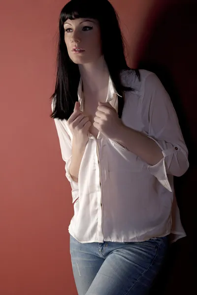 Young woman leaning against a red wall — Stok fotoğraf