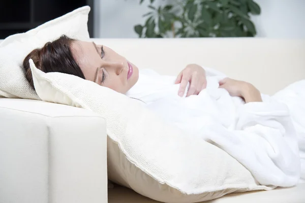 Fiatal nő feküdt egy fehér kanapé — Stock Fotó