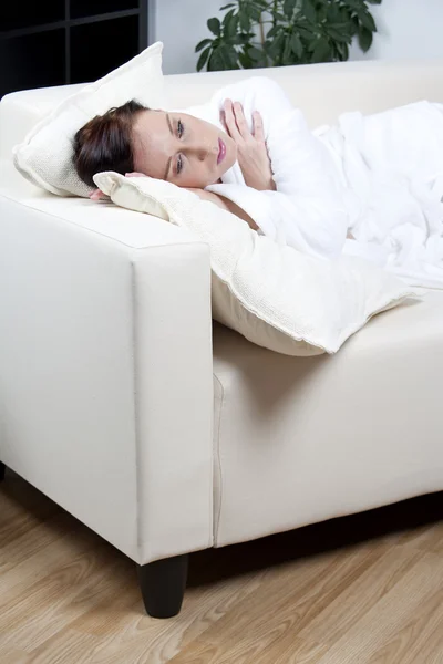 Giovane donna sdraiata su un divano bianco — Foto Stock