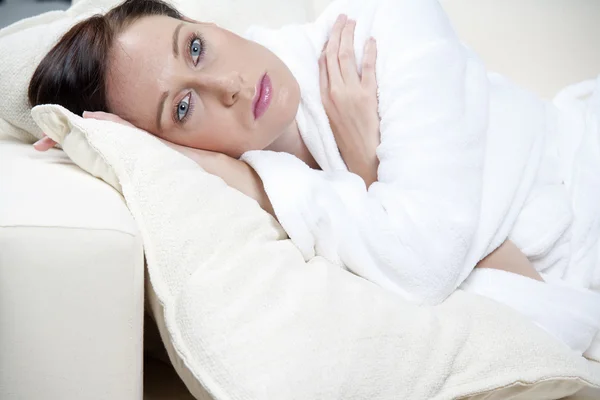 Mladá žena leží na bílé pohovce — Stock fotografie
