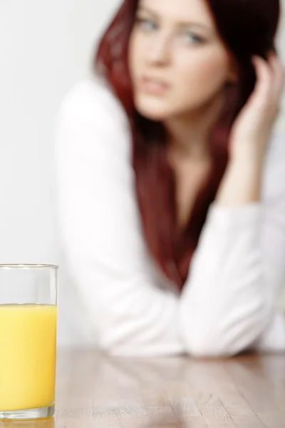 Copo de suco de laranja com mulher no fundo — Fotografia de Stock