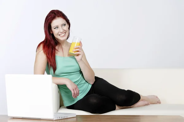 Young woman sat on sofa with laptop — Stock Photo, Image
