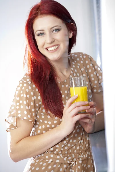 Woman standing by window with juice — Stock Photo, Image