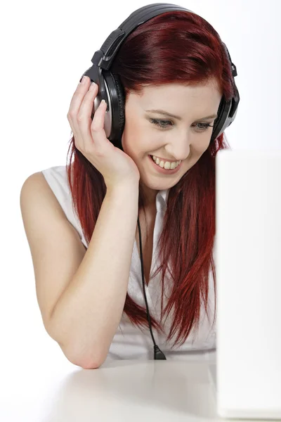 Mulher com fones de ouvido trabalhando no laptop — Fotografia de Stock