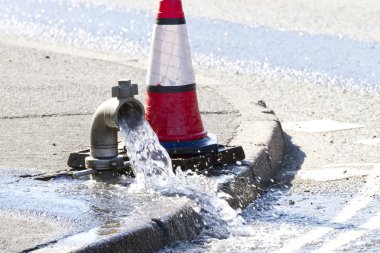 Water being released while a water main is repaired clipart