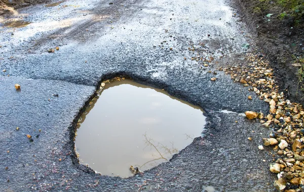 Profundo, buraco cheio de água na estrada — Fotografia de Stock