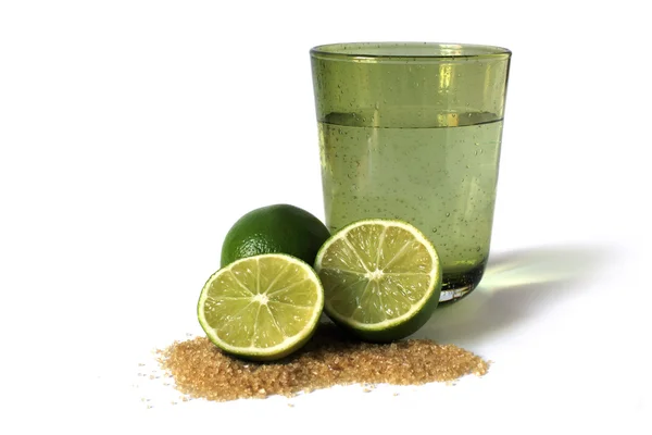 stock image Limes, sugar cane and green glass with water