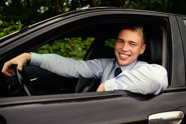 Młody człowiek siedzący w samochodzie uśmiechający się — Zdjęcie stockowe