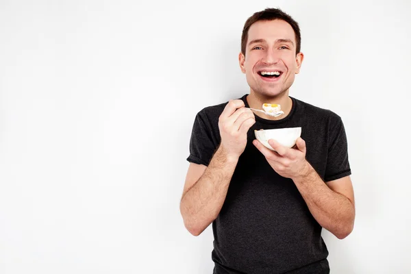 Молодой улыбающийся человек ест мюсли — стоковое фото