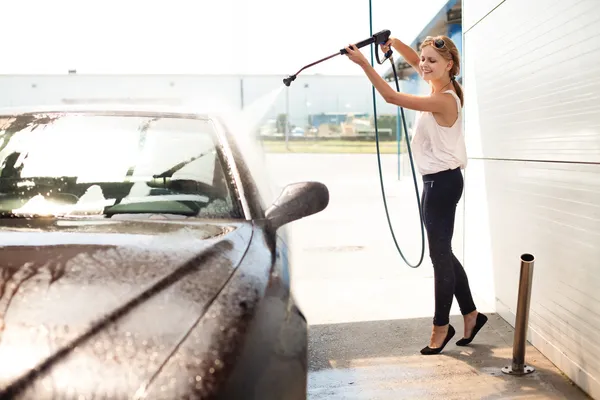 Молодая женщина моет машину — стоковое фото