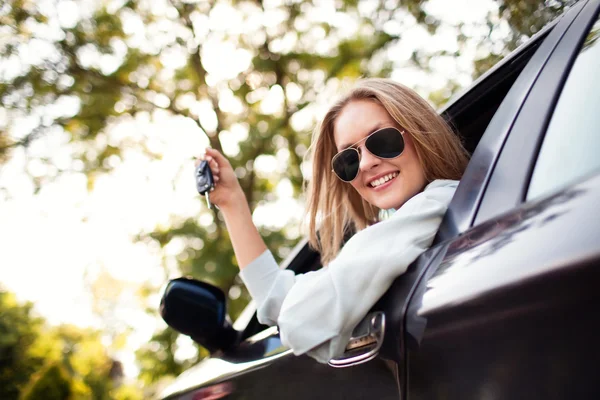 Junge Frau zeigt Schlüssel zu ihrem neuen Auto — Stockfoto