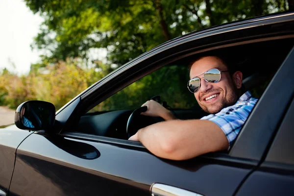 Молодой человек в машине улыбается — стоковое фото