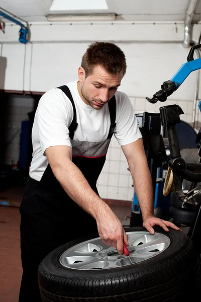 Mechanic fixing tyre in car service — Stock Photo, Image
