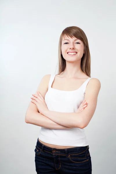 Młoda kobieta stojąc ze skrzyżowanymi rękami. uśmiechający się — Zdjęcie stockowe