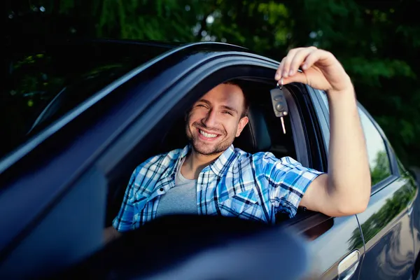 Młody człowiek z kluczami nowy samochód uśmiechnięta — Zdjęcie stockowe