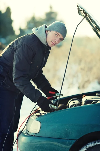 Omul repara masina sparta cu sârmă de acumulator în timpul iernii — Fotografie, imagine de stoc