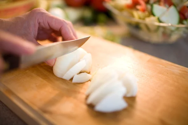 Cutting the onions on a wooden board — Stock Photo, Image