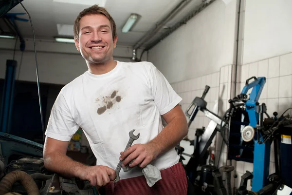 Happy car mechanic standing with wrench tool — Stock Photo, Image