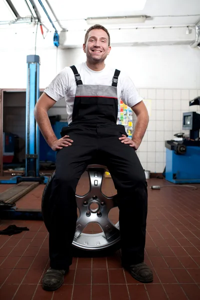 Happy mechanic sitting on the wheel — Stock Photo, Image