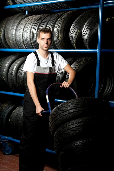 Auto mechanic carrying tire in car service — Stock Photo, Image