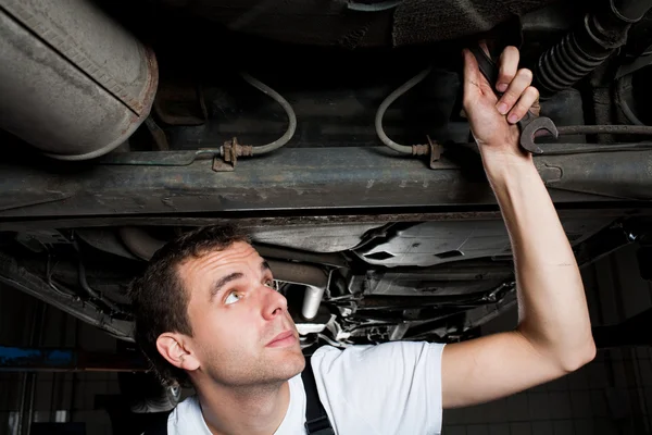 Zbliżenie mechanik pracy poniżej samochód z kluczem — Zdjęcie stockowe