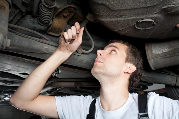 Nahaufnahme eines Mechanikers, der mit einem Schraubenschlüssel unter dem Auto arbeitet — Stockfoto