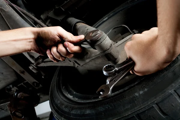 Closeup of mechanics hands working below car with wrench — Stock Photo, Image