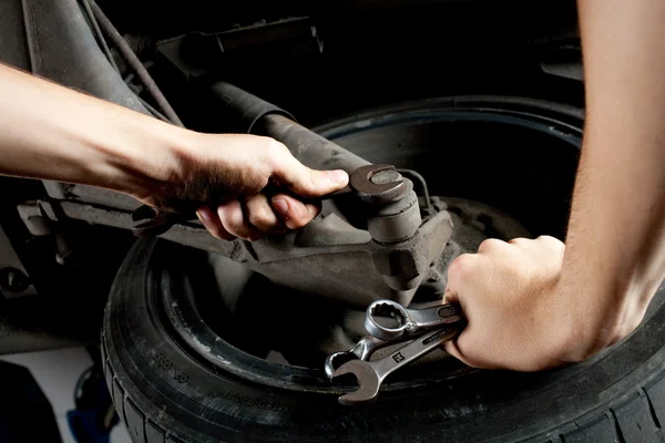 Closeup of mechanics hands working below car with wrench — Stock Photo, Image