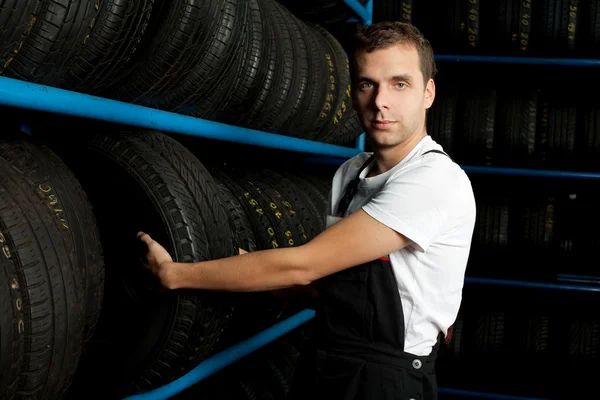 Mecánico de coche eligiendo neumático en tienda de neumáticos — Foto de Stock