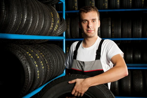 Auto mecânico transportando pneu no serviço de carro — Fotografia de Stock