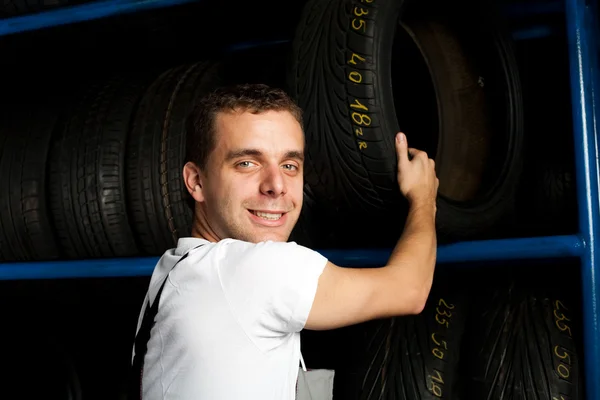 Car mechanic reaching tire in car service — Stock Photo, Image