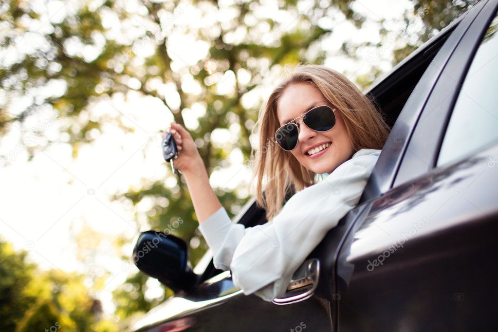 Young woman shows the keys to her new car