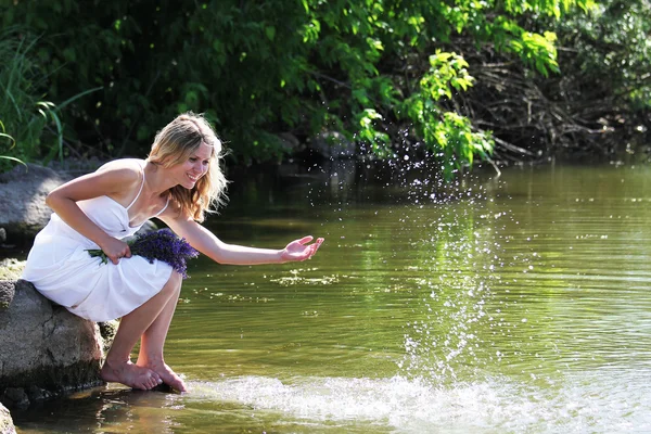 Mujer joven rocía agua cerca del lago —  Fotos de Stock