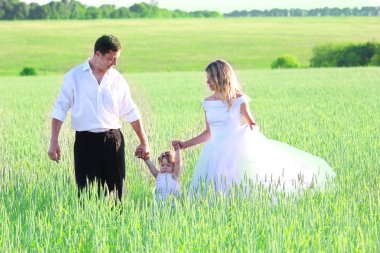 Couple with a baby in a field of wheat clipart