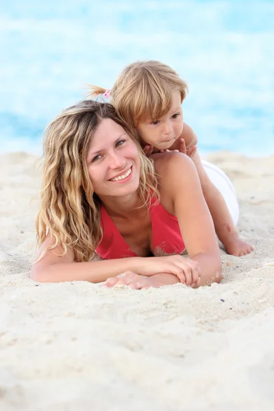 Mamma leker med barnet på stranden vid havet — Stockfoto