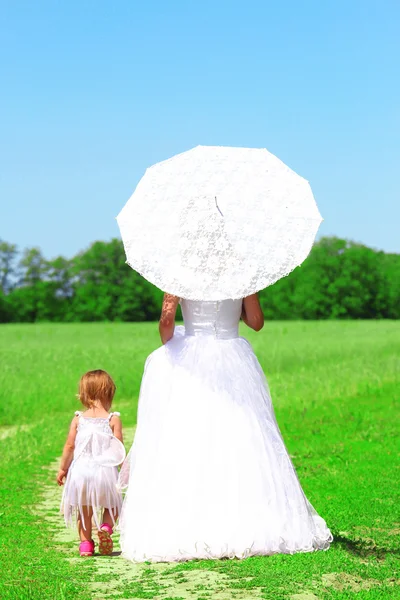 De bruid met een baby in een veld — Stockfoto