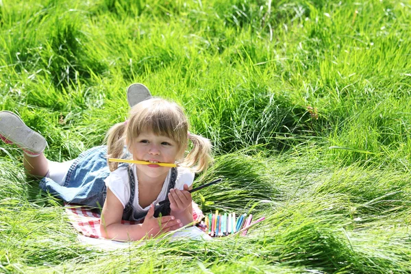 Una hermosa niña con lápices de dibujo sobre la naturaleza —  Fotos de Stock