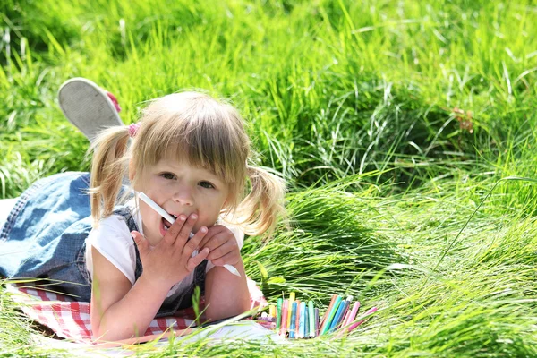 Красивая маленькая девочка с карандашами на природе — стоковое фото