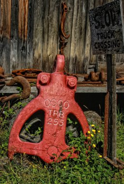 Old logging equipment near a Slow Trucking Crossing Sign clipart