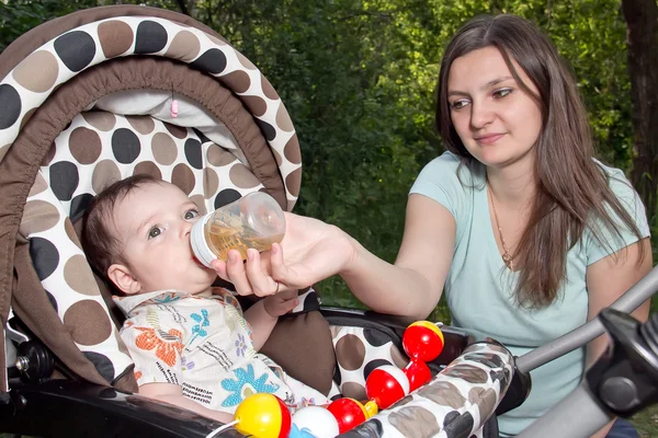 Mother feeding newborn son with feeding bottle — Stock Photo, Image
