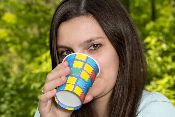 A young woman is drinking from a paper Cup — Stock Photo, Image